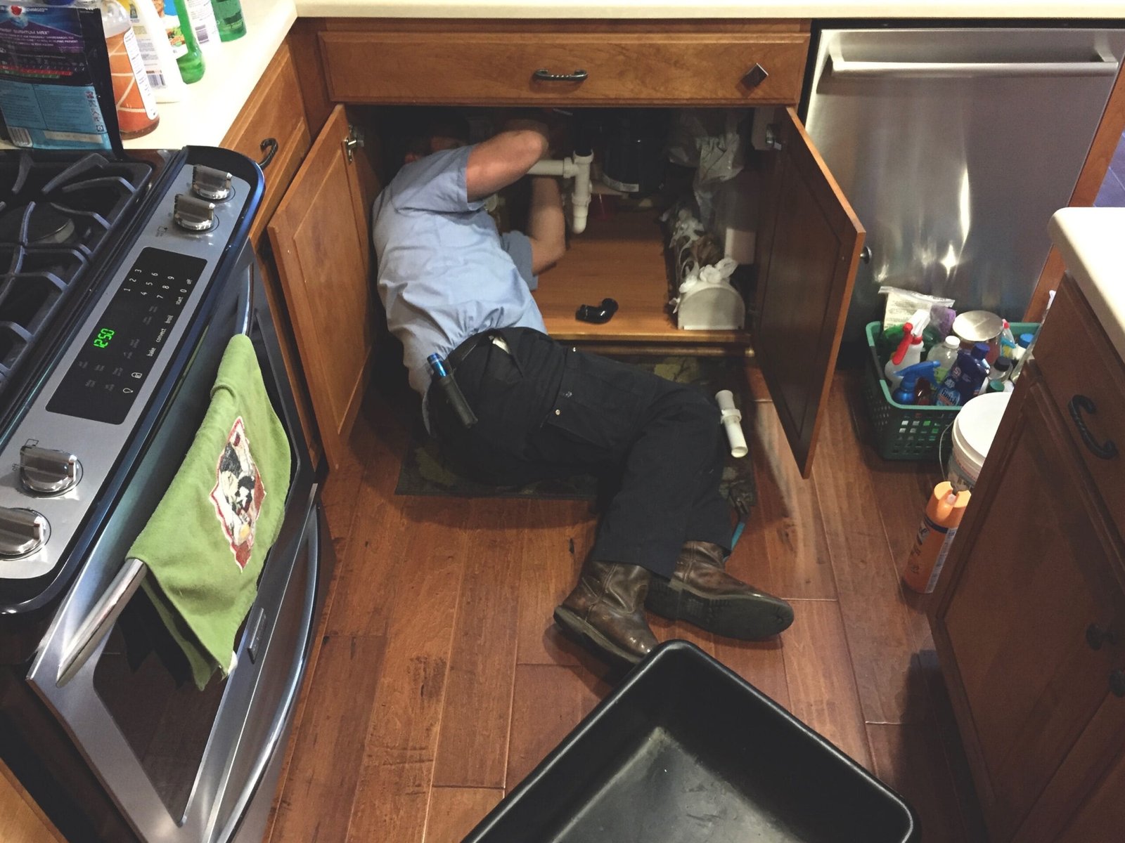 man working under the kitchen sinkfixing the plum garbage disposal reset